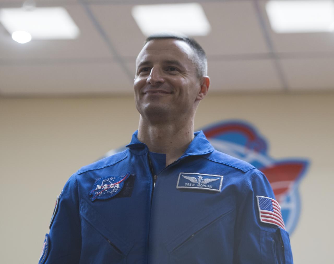 Expedition 58 backup crew member, Flight Engineer Andrew Morgan of NASA, is recognized during a press conference, Sunday, Dec. 2, 2018 at the Cosmonaut Hotel in Baikonur, Kazakhstan. Launch of the Soyuz rocket is scheduled for Dec. 3 and will carry Soyuz Commander Oleg Kononenko of Roscosmos, Flight Engineer Anne McClain of NASA, and Flight Engineer David Saint-Jacques of the Canadian Space Agency (CSA) into orbit to begin their six and a half month mission on the International Space Station. Photo Credit: (NASA/Aubrey Gemignani).