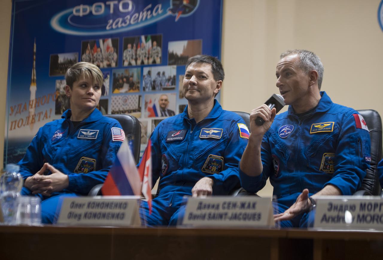 Expedition 58 Flight Engineer David Saint-Jacques answers a question during a press conference, Sunday, Dec. 2, 2018 at the Cosmonaut Hotel in Baikonur, Kazakhstan. He is seen with fellow crewmates Flight Engineer Anne McClain of NASA, left, and Soyuz Commander Oleg Kononenko of Roscosmos, center. Launch of the Soyuz rocket is scheduled for Dec. 3 and will carry Kononenko, McClain, and Saint-Jacques into orbit to begin their six and a half month mission on the International Space Station. Photo Credit: (NASA/Aubrey Gemignani).