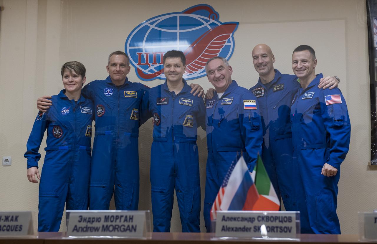Expedition 58 prime crew members, left to right, Flight Engineer Anne McClain of NASA, Flight Engineer David Saint-Jacques of the Canadian Space Agency (CSA), and Soyuz Commander Oleg Kononenko of Roscosmos, pose for a photo with backup crew members Soyuz Commander Alexander Skvortsov of Roscosmos, Flight Engineer Luca Parmitano of ESA (European Space Agency), and Flight Engineer Andrew Morgan of NASA at the conclusion of a press conference, Sunday, Dec. 2, 2018 at the Cosmonaut Hotel in Baikonur, Kazakhstan. Launch of the Soyuz rocket is scheduled for Dec. 3 and will carry Kononenko, McClain, and Saint-Jacques into orbit to begin their six and a half month mission on the International Space Station. Photo Credit: (NASA/Aubrey Gemignani).