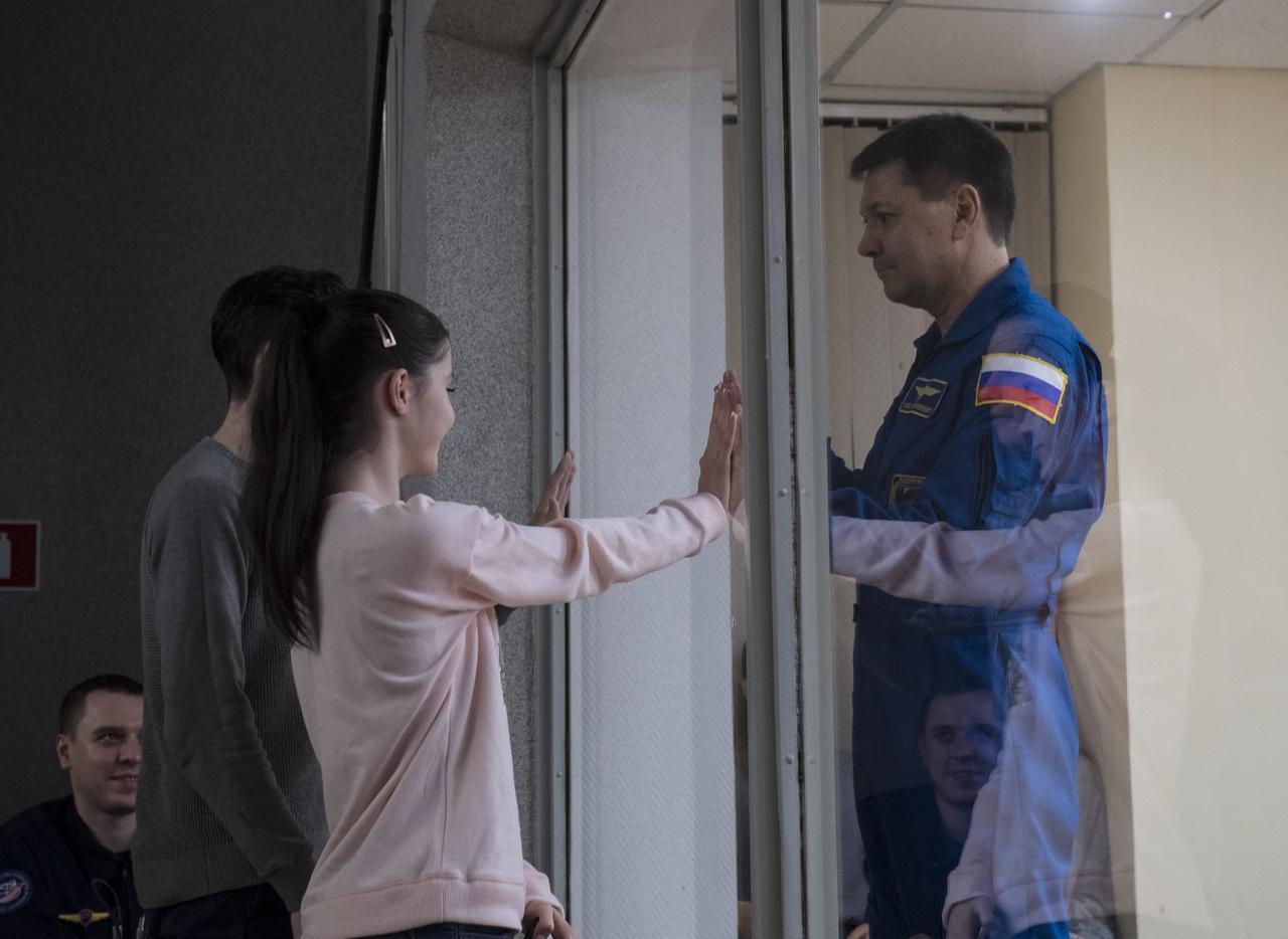 Expedition 58 Soyuz Commander Oleg Kononenko of Roscosmos, right, who is in quarantine, puts his hands up to the glass to meet his daughter at the conclusion of a press conference, Sunday, Dec. 2, 2018 at the Cosmonaut Hotel in Baikonur, Kazakhstan. Launch of the Soyuz rocket is scheduled for Dec. 3 and will carry Kononenko, Flight Engineer Anne McClain of NASA, and Flight Engineer David Saint-Jacques of the Canadian Space Agency (CSA) into orbit to begin their six and a half month mission on the International Space Station. Photo Credit: (NASA/Aubrey Gemignani).