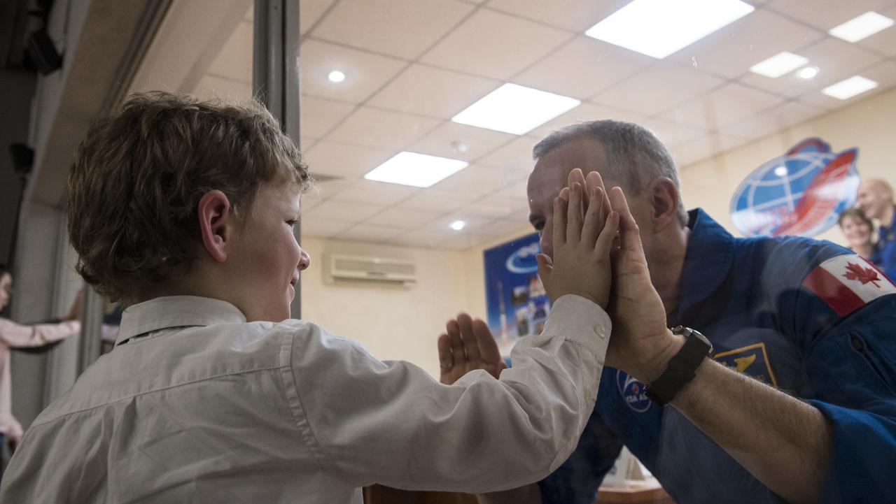 Expedition 58 Flight Engineer David Saint-Jacques of the Canadian Space Agency (CSA), right, who is in quarantine, puts his hands up to the glass to meet his son at the conclusion of a press conference, Sunday, Dec. 2, 2018 at the Cosmonaut Hotel in Baikonur, Kazakhstan. Launch of the Soyuz rocket is scheduled for Dec. 3 and will carry Saint-Jacques, Soyuz Commander Oleg Kononenko of Roscosmos, and Flight Engineer Anne McClain of NASA into orbit to begin their six and a half month mission on the International Space Station. Photo Credit: (NASA/Aubrey Gemignani).