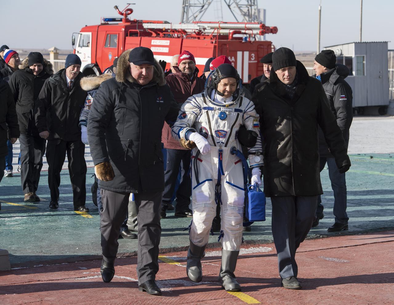 Expedition 58 Soyuz Commander Oleg Kononenko of Roscosmos is walked to the Soyuz vehicle for launch by Dmitry Rogozin, Director General of Roscosmos, left, Monday, Dec. 3, 2018 in Baikonur, Kazakhstan. Kononenko, Flight Engineer Anne McClain of NASA, and Flight Engineer David Saint-Jacques of the Canadian Space Agency (CSA) will spend the next six and a half months onboard the International Space Station. Photo Credit: (NASA/Aubrey Gemignani)