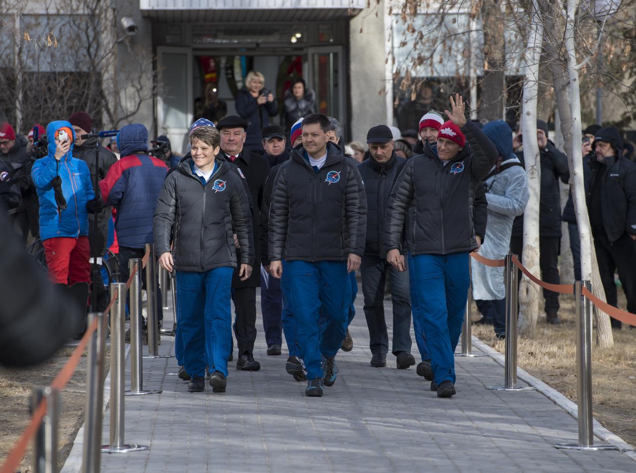 Expedition 58 crew members, Flight Engineer Anne McClain of NASA, left, Soyuz Commander Oleg Kononenko of Roscosmos, center, and Flight Engineer David Saint-Jacques of the Canadian Space Agency (CSA), right, wave farewell to family and friends as they depart the Cosmonaut Hotel to suit-up for their Soyuz launch to the International Space Station on Monday, Dec. 3, 2018 in Baikonur, Kazakhstan. Launch of the Soyuz rocket is scheduled for Dec. 3 and will send Kononenko, McClain, and Saint-Jacques on a six and a half month mission aboard the International Space Station. Photo Credit: (NASA/Aubrey Gemignani)