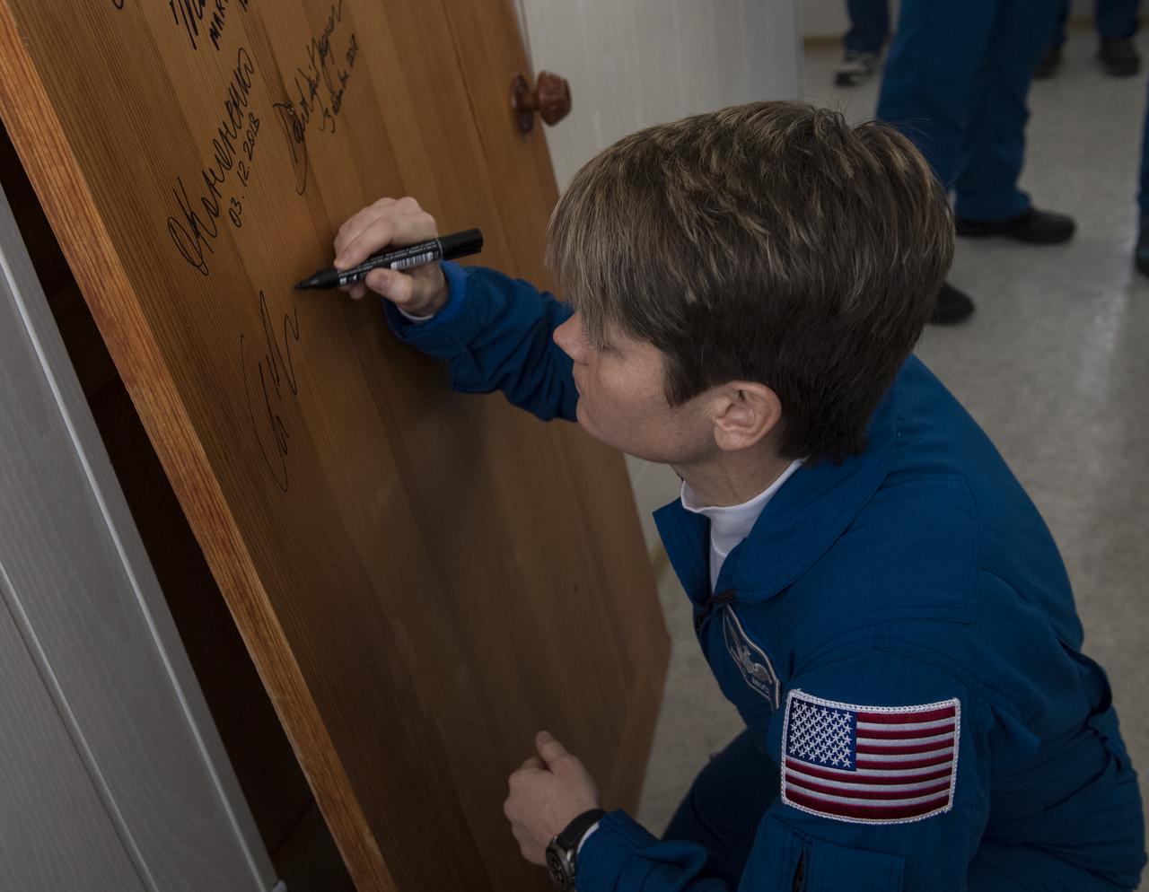 Expedition 58 Flight Engineer Anne McClain of NASA performs the traditional door signing at the Cosmonaut Hotel prior to departing the hotel for launch in a Soyuz rocket with fellow crewmates, Soyuz Commander Oleg Kononenko of Roscosmos, and Flight Engineer David Saint-Jacques of the Canadian Space Agency (CSA), Monday, Dec. 3, 2018, in Baikonur, Kazakhstan. Launch of the Soyuz rocket is scheduled for the same day and will carry McClain, Kononenko, and Saint-Jacques into orbit to begin their six and a half month mission on the International Space Station. Photo Credit: (NASA/Aubrey Gemignani)