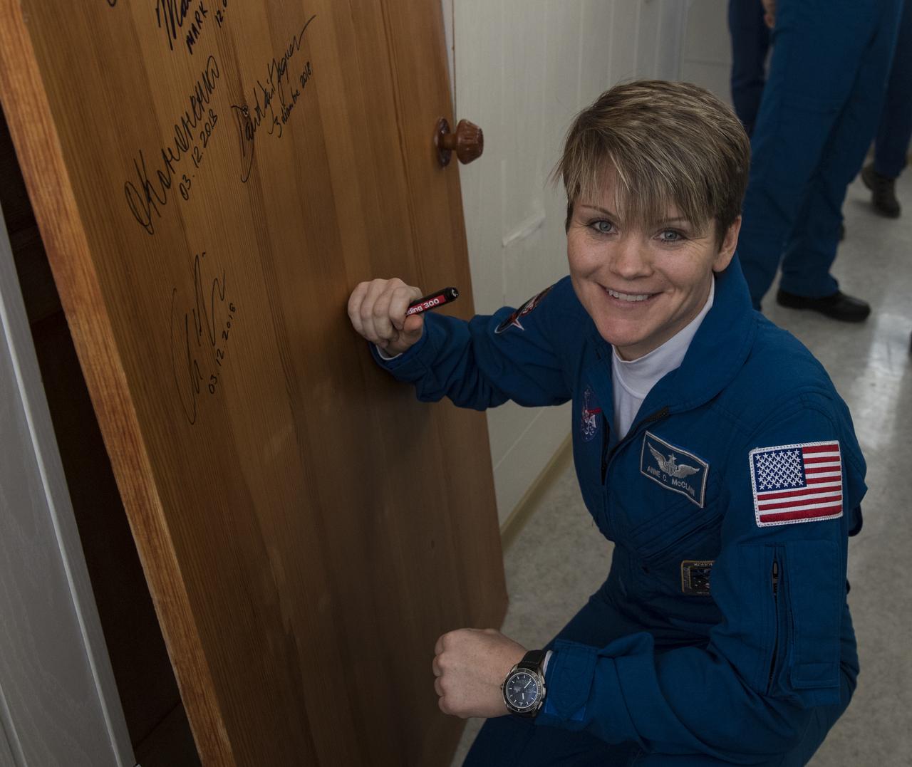 Expedition 58 Flight Engineer Anne McClain of NASA performs the traditional door signing at the Cosmonaut Hotel prior to departing the hotel for launch in a Soyuz rocket with fellow crewmates, Soyuz Commander Oleg Kononenko of Roscosmos, and Flight Engineer David Saint-Jacques of the Canadian Space Agency (CSA), Monday, Dec. 3, 2018, in Baikonur, Kazakhstan. Launch of the Soyuz rocket is scheduled for the same day and will carry McClain, Kononenko, and Saint-Jacques into orbit to begin their six and a half month mission on the International Space Station. Photo Credit: (NASA/Aubrey Gemignani)