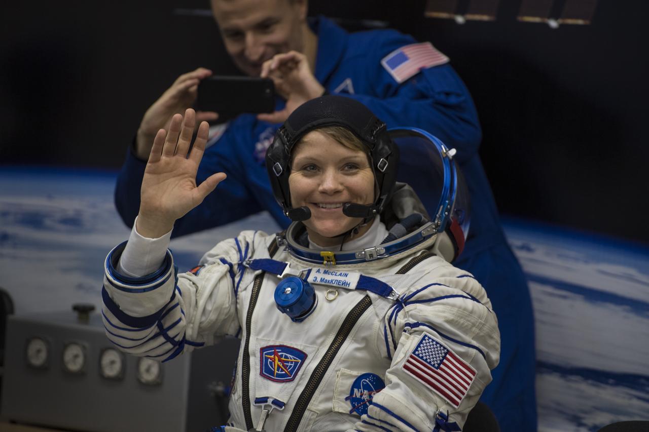 Expedition 58 Flight Engineer Anne McClain of NASA waves at the media while waiting to have her Russian Sokol suit pressure checked in preparation for her launch aboard the Soyuz MS-11 spacecraft on Monday, Dec. 3, 2018, at the Baikonur Cosmodrome in Kazakhstan. Launch of the Soyuz rocket is scheduled for the same day and will carry McClain, Soyuz Commander Oleg Kononenko of Roscosmos, and Flight Engineer David Saint-Jacques of the Canadian Space Agency (CSA) into orbit to begin their six and a half month mission on the International Space Station. Photo Credit: (NASA/Aubrey Gemignani)