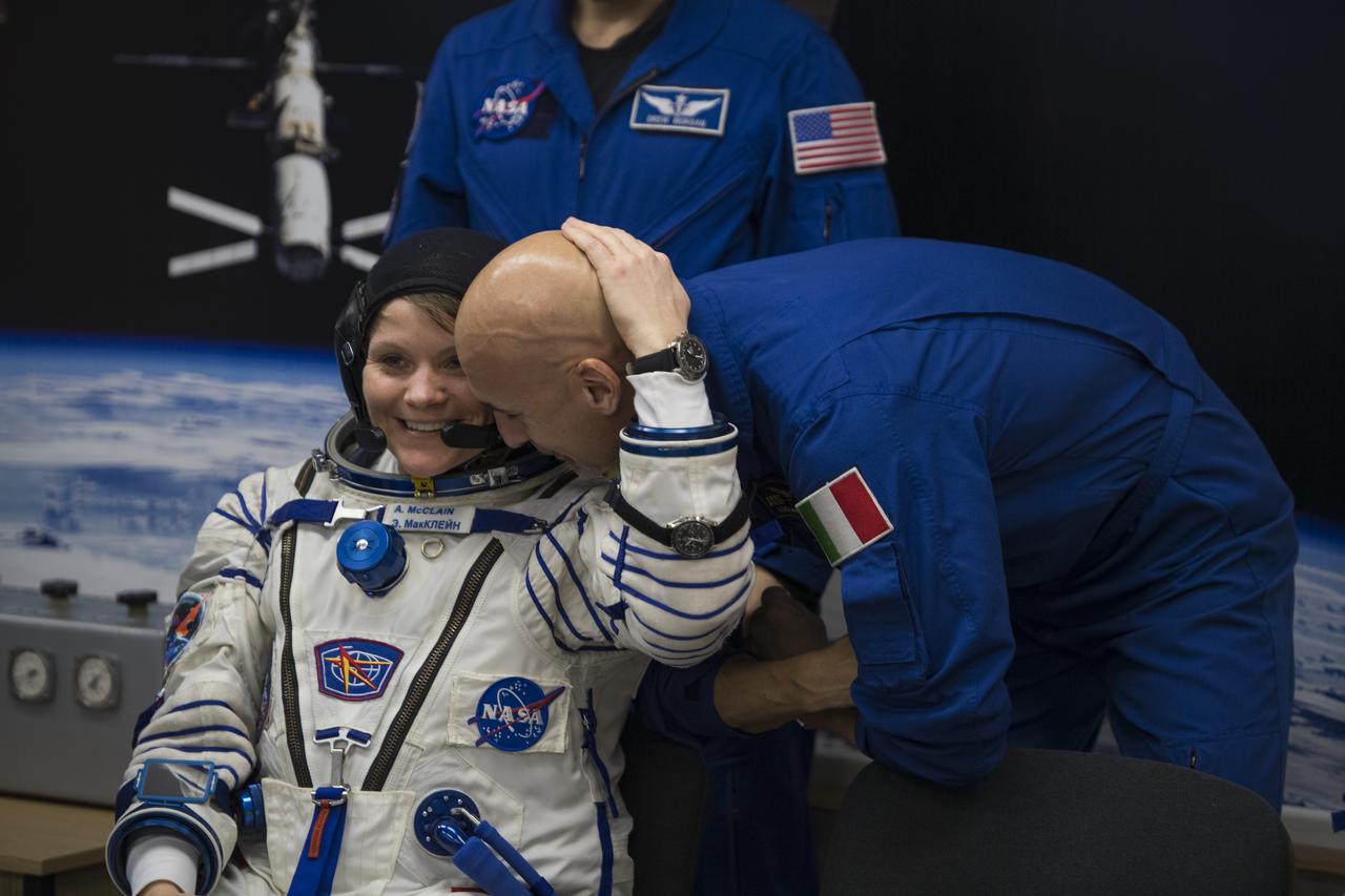 Expedition 58 Flight Engineer Anne McClain of NASA hugs backup crew member Luca Parmitano of ESA (European Space Agency) while she waits to have her Russian Sokol suit pressure checked in preparation for her launch aboard the Soyuz MS-11 spacecraft on Monday, Dec. 3, 2018, at the Baikonur Cosmodrome in Kazakhstan. Launch of the Soyuz rocket is scheduled for the same day and will carry McClain, Soyuz Commander Oleg Kononenko of Roscosmos, and Flight Engineer David Saint-Jacques of the Canadian Space Agency (CSA) into orbit to begin their six and a half month mission on the International Space Station. Photo Credit: (NASA/Aubrey Gemignani)