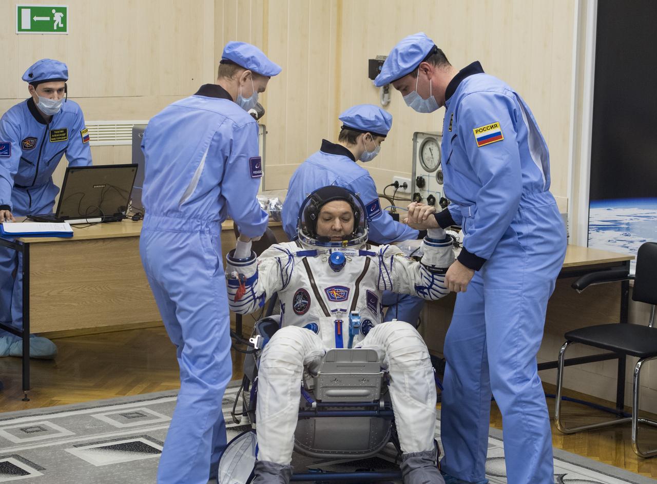 Expedition 58 Soyuz Commander Oleg Kononenko of Roscosmos is helped up after completing his Russian Sokol suit pressure check in preparation for his launch aboard the Soyuz MS-11 spacecraft on Monday, Dec. 3, 2018, at the Baikonur Cosmodrome in Kazakhstan. Launch of the Soyuz rocket is scheduled for the same day and will carry Kononenko, Flight Engineer Anne McClain of NASA, and Flight Engineer David Saint-Jacques of the Canadian Space Agency (CSA) into orbit to begin their six and a half month mission on the International Space Station. Photo Credit: (NASA/Aubrey Gemignani)