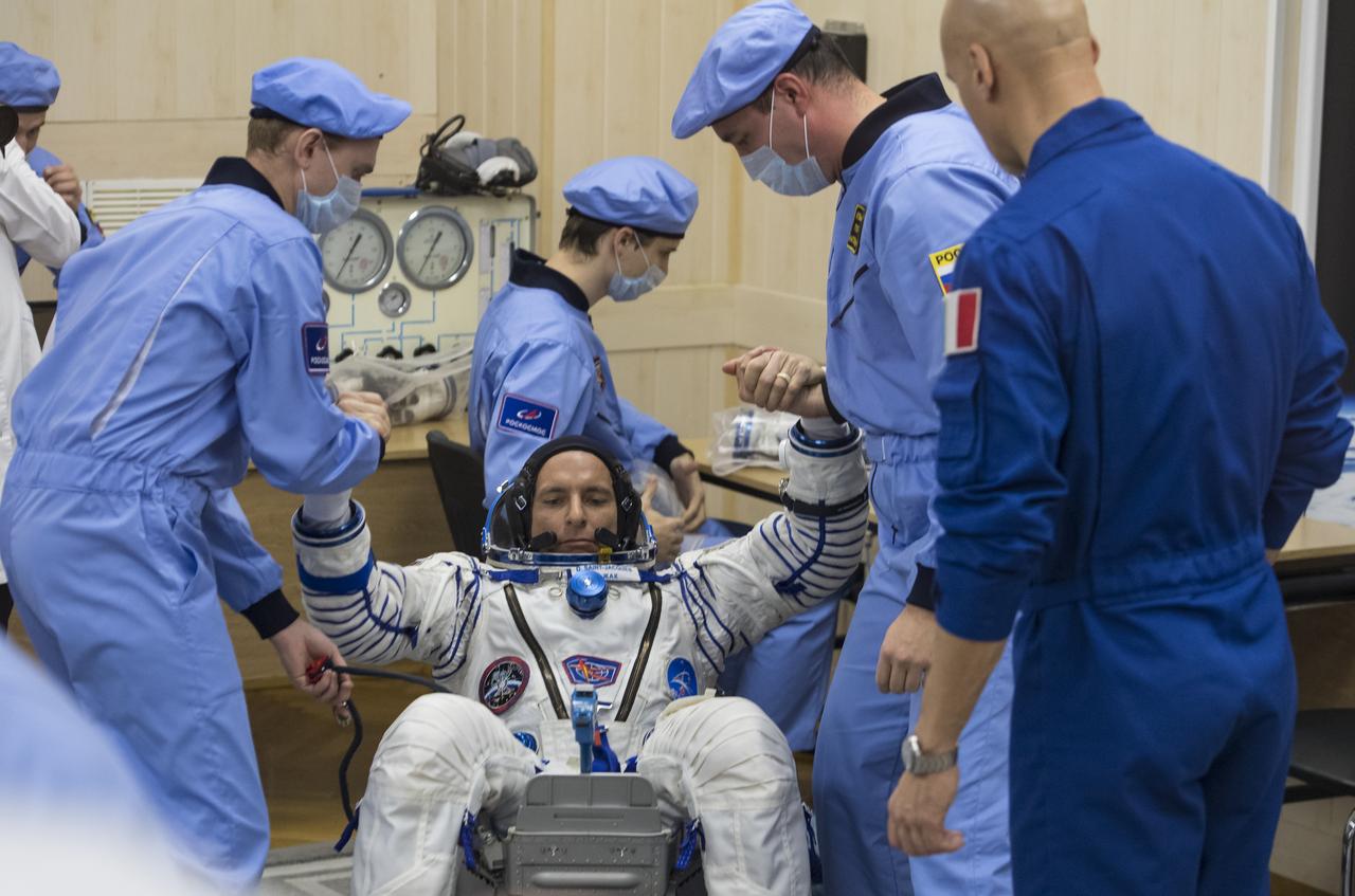 Expedition 58 Flight Engineer David Saint-Jacques of the Canadian Space Agency (CSA) is helped up after completing his Russian Sokol suit pressure check in preparation for his launch aboard the Soyuz MS-11 spacecraft on Monday, Dec. 3, 2018, at the Baikonur Cosmodrome in Kazakhstan. Launch of the Soyuz rocket is scheduled for the same day and will carry Saint-Jacques, Flight Engineer Anne McClain of NASA, and Soyuz Commander Oleg Kononenko of Roscosmos into orbit to begin their six and a half month mission on the International Space Station. Photo Credit: (NASA/Aubrey Gemignani)