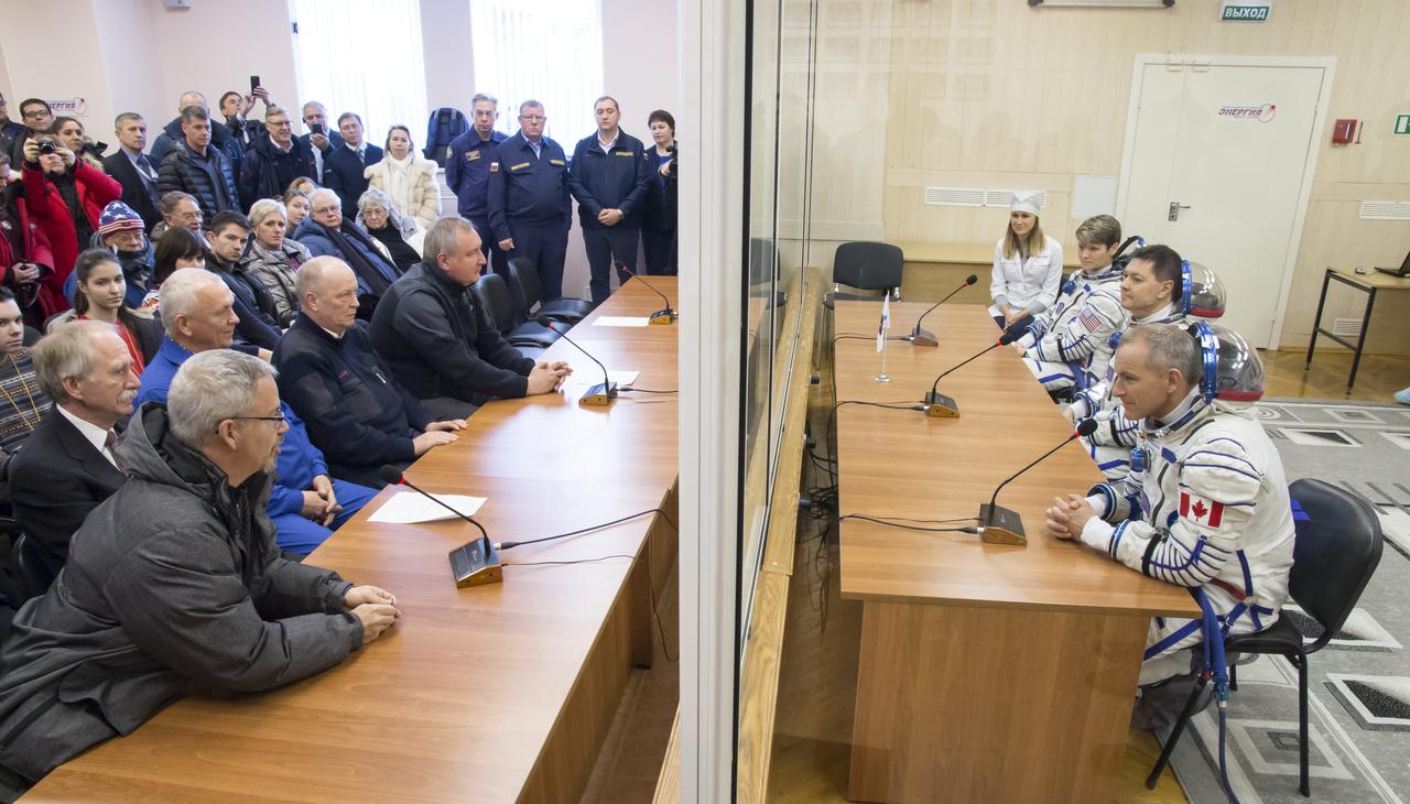 Expedition 58 crew, from top right to bottom right, Flight Engineer Anne McClain of NASA, Soyuz Commander Oleg Kononenko of Roscosmos, and Flight Engineer David Saint-Jacques of the Canadian Space Agency (CSA) speak to leadership of Roscosmos, NASA, and the CSA after having their Russian Sokol suits pressure checked in preparation for their launch aboard the Soyuz MS-11 spacecraft on Monday, Dec. 3, 2018, at the Baikonur Cosmodrome in Kazakhstan. Launch of the Soyuz rocket is scheduled for the same day and will carry Kononenko, Saint-Jacques, and McClain into orbit to begin their six and a half month mission on the International Space Station. Photo Credit: (NASA/Victor Zelentsov)