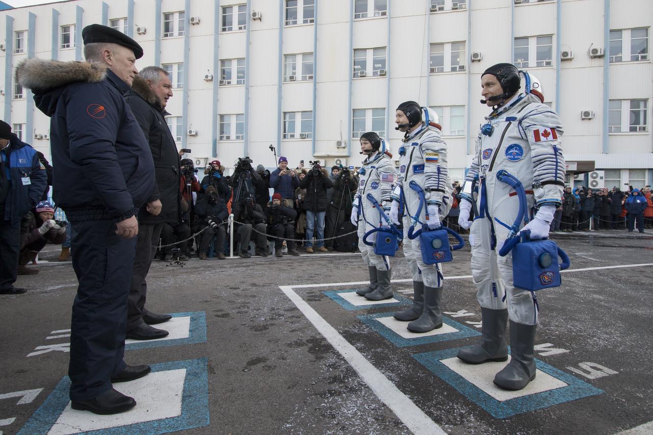 Expedition 58 crew, from top right to bottom right, Flight Engineer Anne McClain of NASA, Soyuz Commander Oleg Kononenko of Roscosmos, and Flight Engineer David Saint-Jacques of the Canadian Space Agency (CSA) walk out of building 254 to meet with leadership of Roscosmos after having their Russian Sokol suits pressure checked in preparation for their launch aboard the Soyuz MS-11 spacecraft on Monday, Dec. 3, 2018, at the Baikonur Cosmodrome in Kazakhstan. Launch of the Soyuz rocket is scheduled for the same day and will carry Kononenko, Saint-Jacques, and McClain into orbit to begin their six and a half month mission on the International Space Station. Photo Credit: (NASA/Victor Zelentsov)