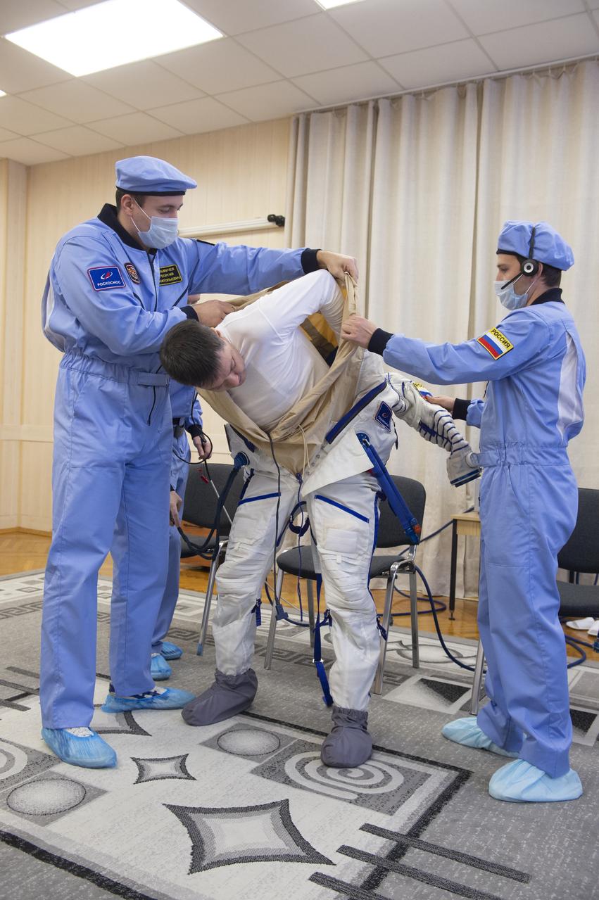 Expedition 58 Soyuz Commander Oleg Kononenko of Roscosmos is helped into his Russian Sokol suit as he and fellow crewmates, Flight Engineer Anne McClain of NASA and Flight Engineer David Saint-Jacques of the Canadian Space Agency (CSA) prepare for their Soyuz launch to the International Space Station, on Monday, Dec. 3, 2018 at the Baikonur Cosmodrome in Kazakhstan. Launch of the Soyuz rocket is scheduled for the same day and will carry Kononenko, McClain, and Saint-Jacques into orbit to begin their six and a half month mission on the International Space Station. Photo Credit: (GCTC/NASA/Andrey Shelepin)