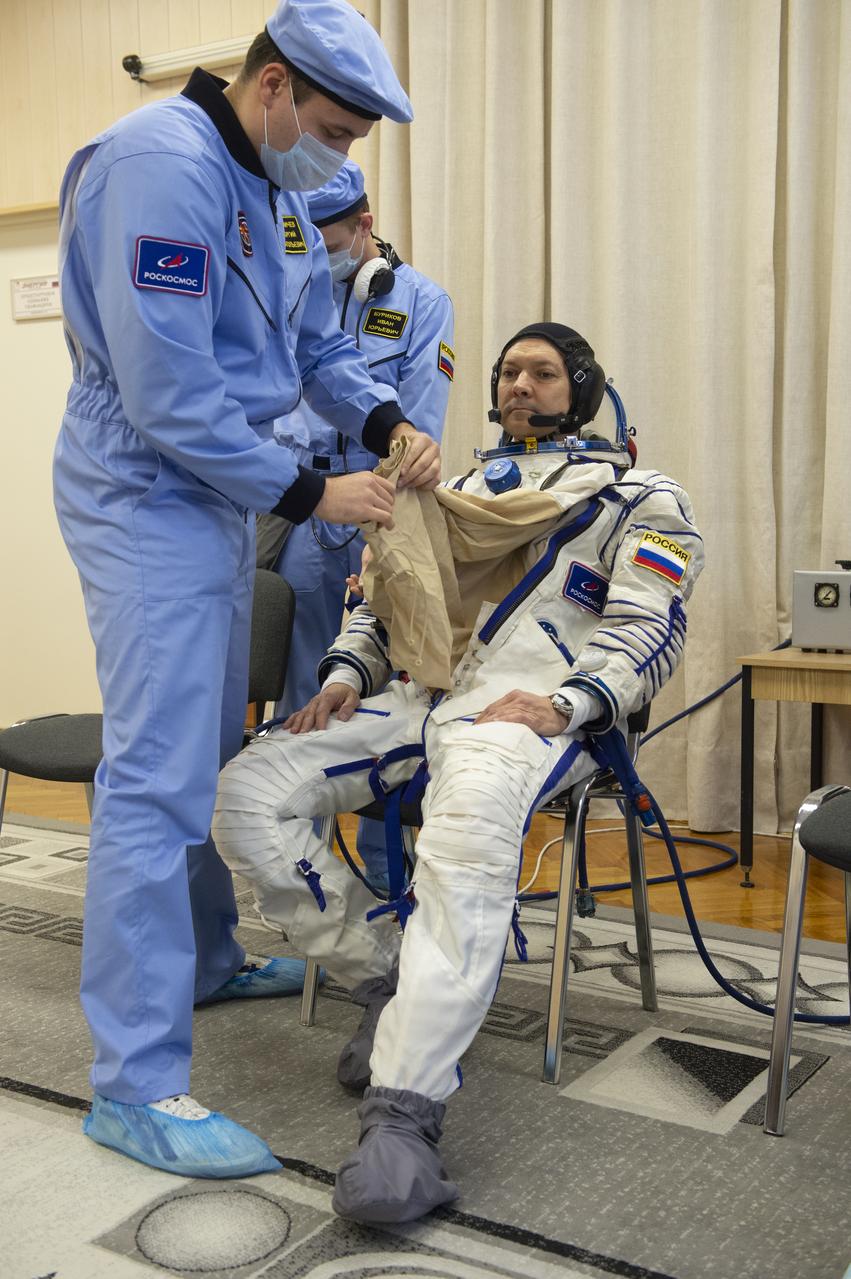 Expedition 58 Soyuz Commander Oleg Kononenko of Roscosmos is helped into his Russian Sokol suit as he and fellow crewmates, Flight Engineer Anne McClain of NASA and Flight Engineer David Saint-Jacques of the Canadian Space Agency (CSA) prepare for their Soyuz launch to the International Space Station, on Monday, Dec. 3, 2018 at the Baikonur Cosmodrome in Kazakhstan. Launch of the Soyuz rocket is scheduled for the same day and will carry Kononenko, McClain, and Saint-Jacques into orbit to begin their six and a half month mission on the International Space Station. Photo Credit: (GCTC/NASA/Andrey Shelepin)