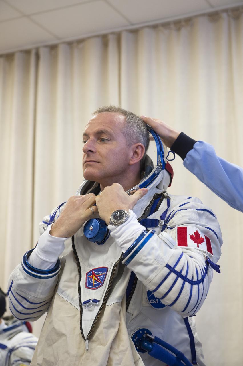 Expedition 58 Flight Engineer David Saint-Jacques of the Canadian Space Agency (CSA) is helped into his Russian Sokol suit as he and fellow crewmates, Flight Engineer Anne McClain of NASA and Soyuz Commander Oleg Kononenko of Roscosmos prepare for their Soyuz launch to the International Space Station, on Monday, Dec. 3, 2018 at the Baikonur Cosmodrome in Kazakhstan. Launch of the Soyuz rocket is scheduled for the same day and will carry Kononenko, McClain, and Saint-Jacques into orbit to begin their six and a half month mission on the International Space Station. Photo Credit: ((GCTC/NASA/Andrey Shelepin))