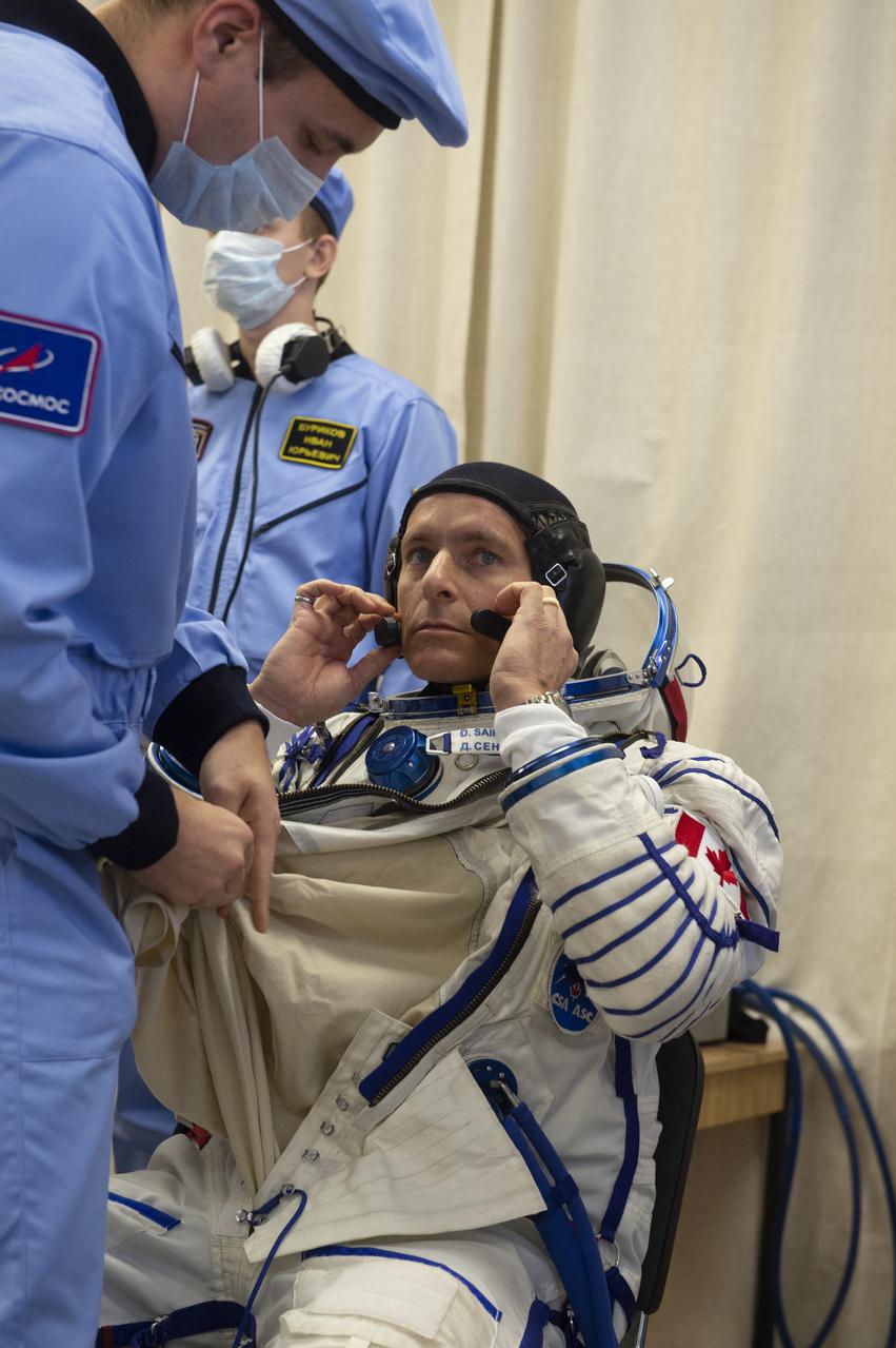 Expedition 58 Flight Engineer David Saint-Jacques of the Canadian Space Agency (CSA) is helped into his Russian Sokol suit as he and fellow crewmates, Flight Engineer Anne McClain of NASA and Soyuz Commander Oleg Kononenko of Roscosmos prepare for their Soyuz launch to the International Space Station, on Monday, Dec. 3, 2018 at the Baikonur Cosmodrome in Kazakhstan. Launch of the Soyuz rocket is scheduled for the same day and will carry Kononenko, McClain, and Saint-Jacques into orbit to begin their six and a half month mission on the International Space Station. Photo Credit: ((GCTC/NASA/Andrey Shelepin))