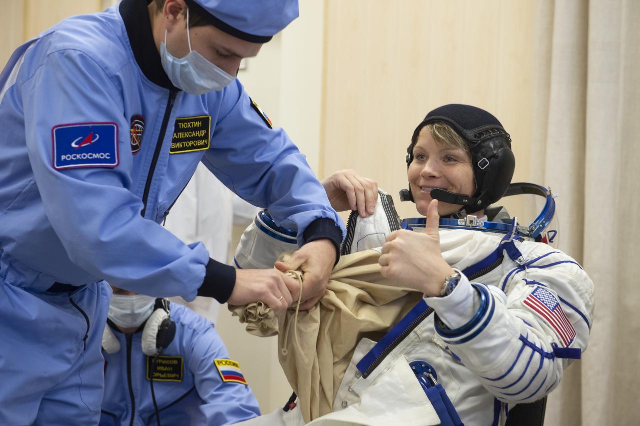 Flight Engineer Anne McClain of NASA is helped into her Russian Sokol suit as she and fellow crewmates, Expedition 58 Soyuz Commander Oleg Kononenko of Roscosmos and Flight Engineer David Saint-Jacques of the Canadian Space Agency (CSA) prepare for their Soyuz launch to the International Space Station, on Monday, Dec. 3, 2018 at the Baikonur Cosmodrome in Kazakhstan. Launch of the Soyuz rocket is scheduled for the same day and will carry McClain, Kononenko, and Saint-Jacques into orbit to begin their six and a half month mission on the International Space Station. Photo Credit: (GCTC/NASA/Andrey Shelepin)