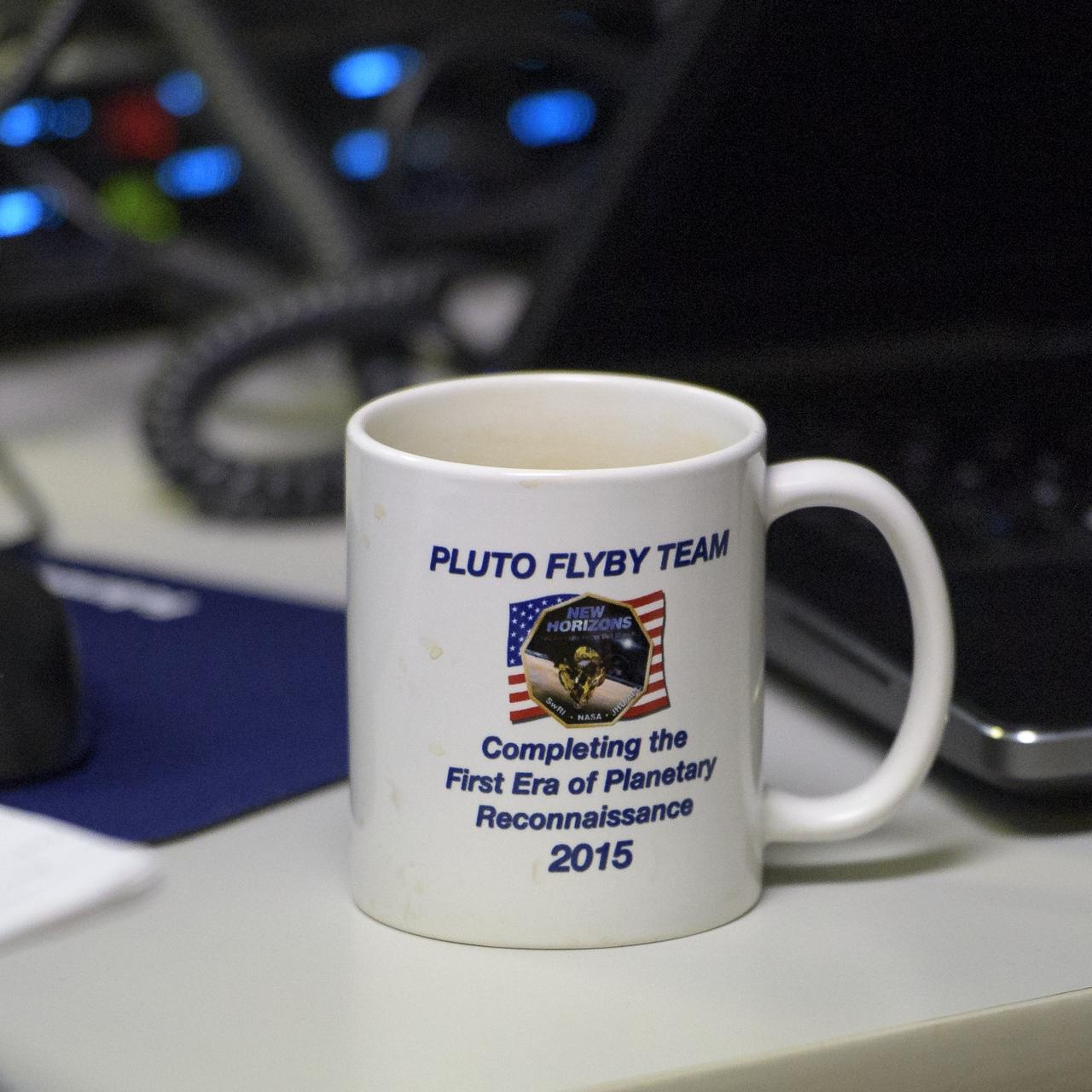 A New Horizons Pluto flyby coffee mug is seen as team members wait for a signal from the spacecraft that it is healthy and collected data during the flyby of Ultima Thule, Tuesday, Jan. 1, 2019 at the Mission Operations Center of the Johns Hopkins University Applied Physics Laboratory (APL) in Laurel, Maryland. Photo Credit: (NASA/Bill Ingalls)