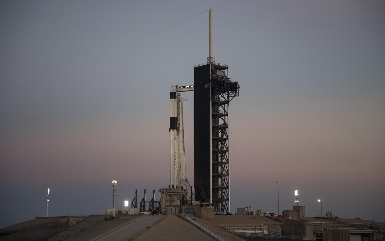 A SpaceX Falcon 9 rocket with the company's Crew Dragon spacecraft onboard is seen after being raised into a vertical position on the launch pad at Launch Complex 39A as preparations continue for the Demo-1 mission, Feb. 28, 2019 at the Kennedy Space Center in Florida. The Demo-1 mission will be the first launch of a commercially built and operated American spacecraft and space system designed for humans as part of NASA's Commercial Crew Program. The mission, currently targeted for a 2:49am launch on March 2, will serve as an end-to-end test of the system's capabilities. Photo Credit: (NASA/Joel Kowsky)