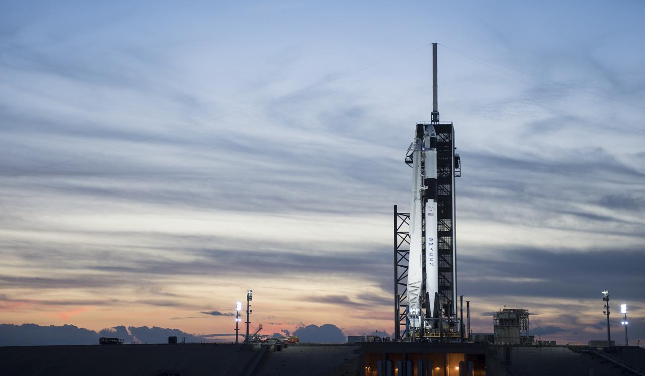 A SpaceX Falcon 9 rocket with the company's Crew Dragon spacecraft onboard is seen after being raised into a vertical position on the launch pad at Launch Complex 39A as preparations continue for the Demo-1 mission, Feb. 28, 2019 at the Kennedy Space Center in Florida. The Demo-1 mission will be the first launch of a commercially built and operated American spacecraft and space system designed for humans as part of NASA's Commercial Crew Program. The mission, currently targeted for a 2:49am launch on March 2, will serve as an end-to-end test of the system's capabilities. Photo Credit: (NASA/Joel Kowsky)