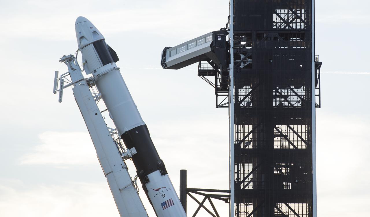 A SpaceX Falcon 9 rocket with the company's Crew Dragon spacecraft onboard is seen as it is raised into a vertical position on the launch pad at Launch Complex 39A as preparations continue for the Demo-1 mission, Feb. 28, 2019 at the Kennedy Space Center in Florida. The Demo-1 mission will be the first launch of a commercially built and operated American spacecraft and space system designed for humans as part of NASA's Commercial Crew Program. The mission, currently targeted for a 2:49am launch on March 2, will serve as an end-to-end test of the system's capabilities. Photo Credit: (NASA/Joel Kowsky)