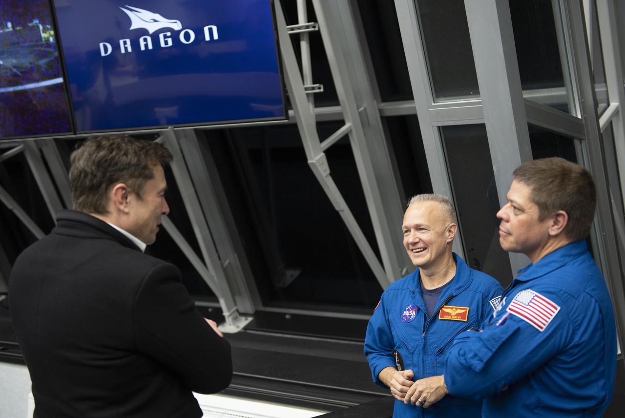 SpaceX CEO and Chief Designer Elon Musk, left, speaks with NASA astronauts Doug Hurley, center, and Bob Behnken, right, who are assigned to fly on the crewed Demo-2 mission after launch of a SpaceX Falcon 9 rocket carrying the company's Crew Dragon spacecraft on the Demo-1 mission from firing room four of the Launch Control Center, Saturday, March 2, 2019 at the Kennedy Space Center in Florida. The Demo-1 mission is the first launch of a commercially built and operated American spacecraft and space system designed for humans as part of NASA's Commercial Crew Program. The mission will serve as an end-to-end test of the system's capabilities. Photo Credit: (NASA/Joel Kowsky)