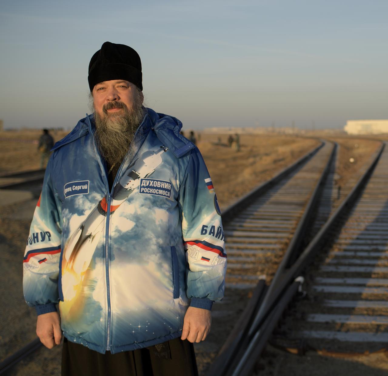 Russian Orthodox Priest Father Sergei poses for a photograph as he waits for the train transporting the Soyuz rocket to the launch pad to pass, Tuesday, March 12, 2019 at the Baikonur Cosmodrome in Kazakhstan. Expedition 59 crewmembers Nick Hague and Christina Koch of NASA, along with Alexey Ovchinin of Roscosmos, will launch March 14, U.S. time, on the Soyuz MS-12 spacecraft from the Baikonur Cosmodrome for a six-and-a-half month mission on the International Space Station. Photo Credit: (NASA/Bill Ingalls)