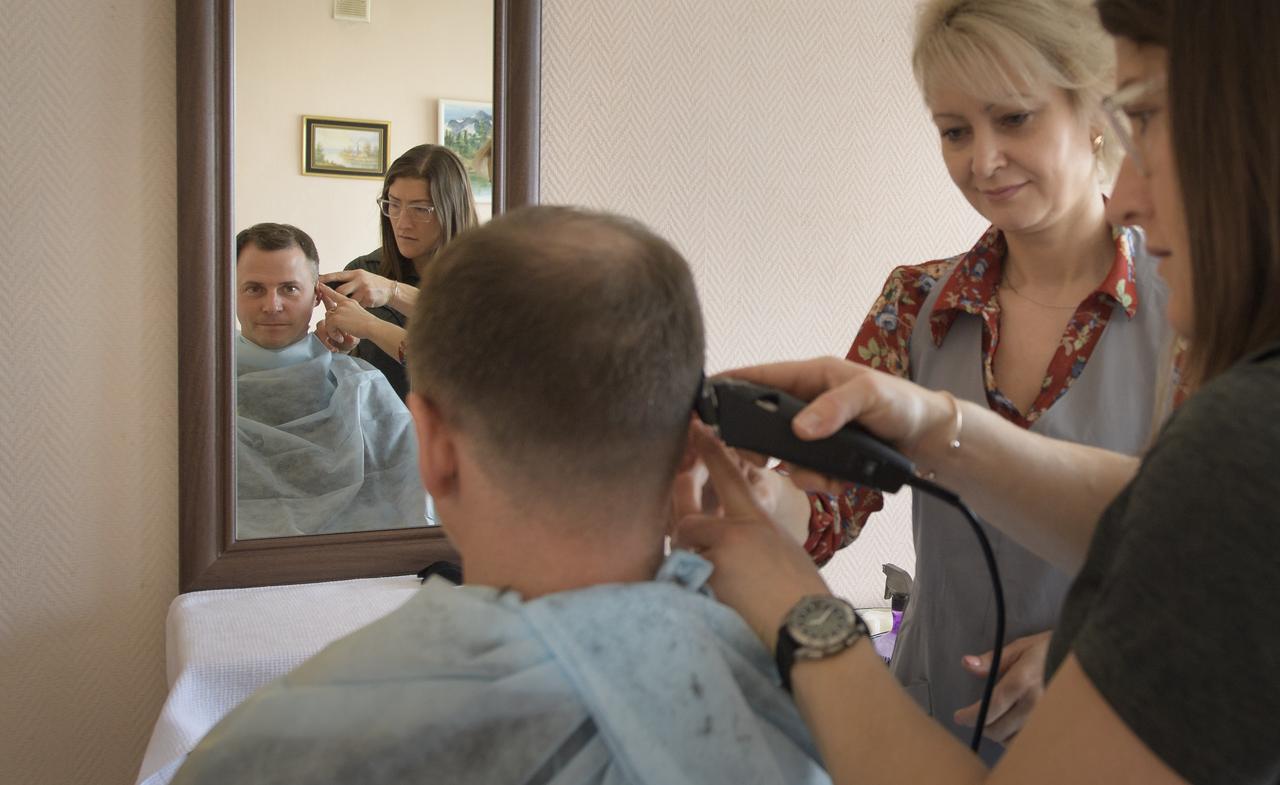 Expedition 59 astronaut Nick Hague of NASA sits as fellow crewmember, astronaut Christina Koch of NASA, is shown how to cut hair by a stylist, Tuesday, March 12, 2019 at the Cosmonaut Hotel in Baikonur, Kazakhstan. Crewmembers often give each other haircuts while onboard the International Space Station. Hague, Koch, and Alexey Ovchinin of Roscosmos, will launch March 14, U.S. time, on the Soyuz MS-12 spacecraft from the Baikonur Cosmodrome for a six-and-a-half month mission on the International Space Station. Photo Credit: (NASA/Bill Ingalls)