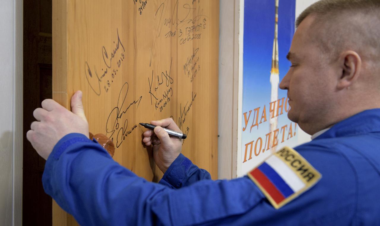 Expedition 59 cosmonaut Alexey Ovchinin of Roscosmos signs a door in the Cosmonaut Hotel prior to departing for launch on a Soyuz rocket with Nick Hague, and Christina Koch of NASA, Thursday, March 14, 2019 in Baikonur, Kazakhstan. Hague, Koch, and Ovchinin will launch March 14, U.S. time, on the Soyuz MS-12 spacecraft from the Baikonur Cosmodrome for a six-and-a-half month mission on the International Space Station. Photo Credit: (NASA/Bill Ingalls)