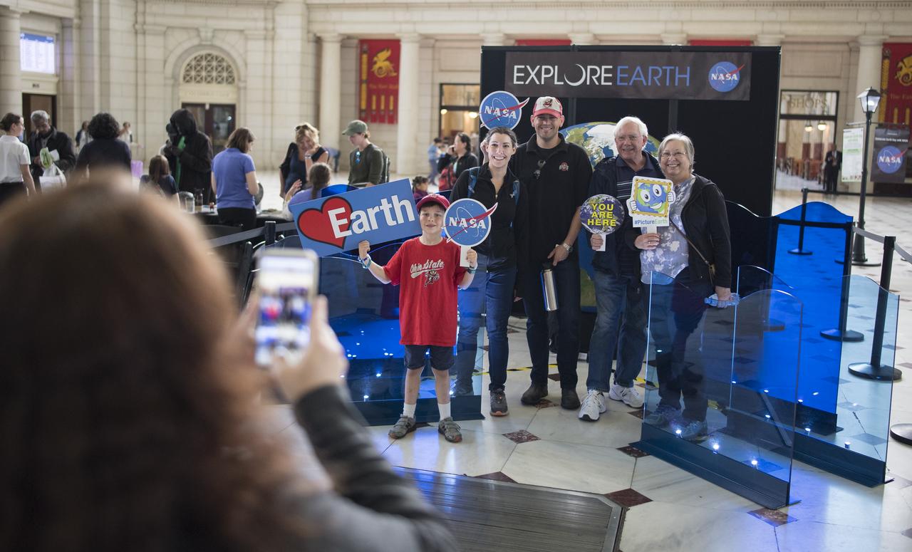 Visitors to NASA's exhibits at the Earth Day event take a picture with a globe, Monday, April 22, 2019, at Union Station in Washington, D.C. Photo Credit: (NASA/Joel Kowsky)