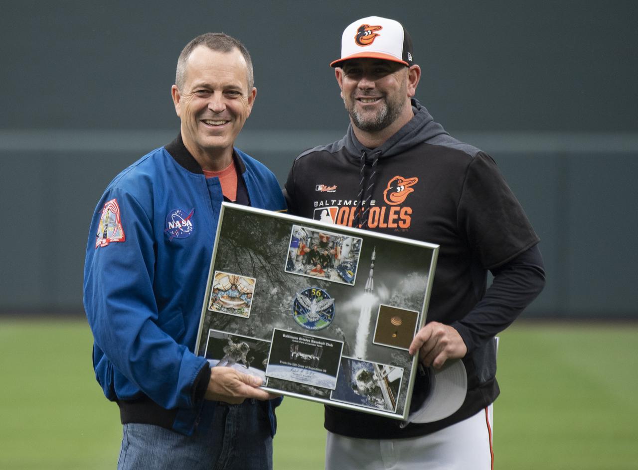 NASA astronaut and Maryland native Ricky Arnold presents a montage of images from his mission and a Baltimore Orioles hat that was flown aboard the International Space Station to Baltimore Orioles manager Brandon Hyde before the Tampa Bay Rays take on the Baltimore Orioles, Saturday, May 4, 2019 at Camden Yards in Baltimore, Md. During Arnold’s 197 days onboard the International Space Station, as part of Expeditions 55 and 56, he ventured outside the space station on three spacewalks in addition to conducting numerous experiments and educational downlink events. Photo Credit: (NASA/Joel Kowsky)