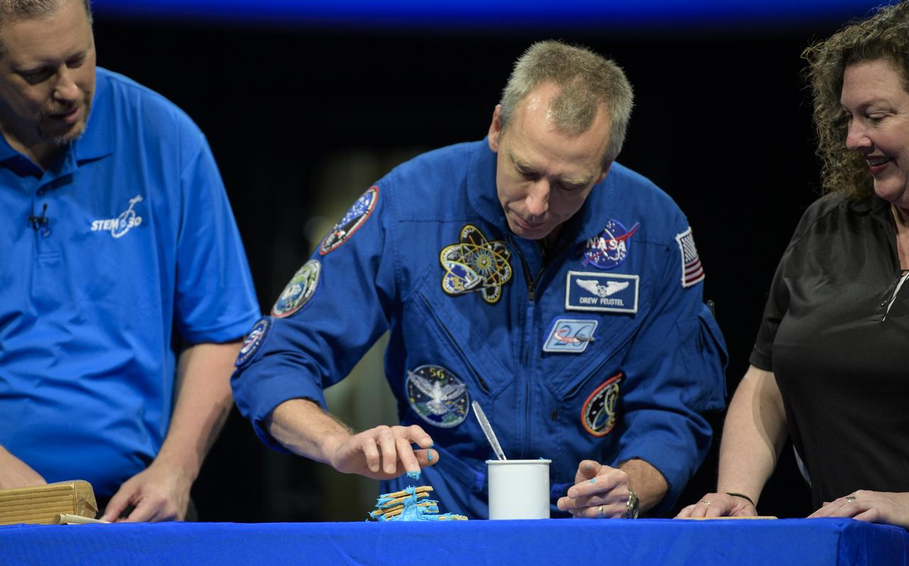 NASA astronaut Drew Feustel, center, uses frosting and graham crackers to represent the layers of Earths crust while taping a segment of STEM in 30 with Marty Kelsey, left, and Beth Wilson, right, Thursday, May 9, 2019 at the Smithsonian’s National Air and Space Museum in Washington, DC. Feustel most recently spent 197 days living and working onboard the International Space Station as part of Expedition 55 and as commander of Expedition 56. Feustel ventured outside the space station on three spacewalks, moving him up to second among U.S. spacewalkers with a cumulative time of 61 hours 48 minutes over nine spacewalks. Photo Credit: (NASA/Joel Kowsky)