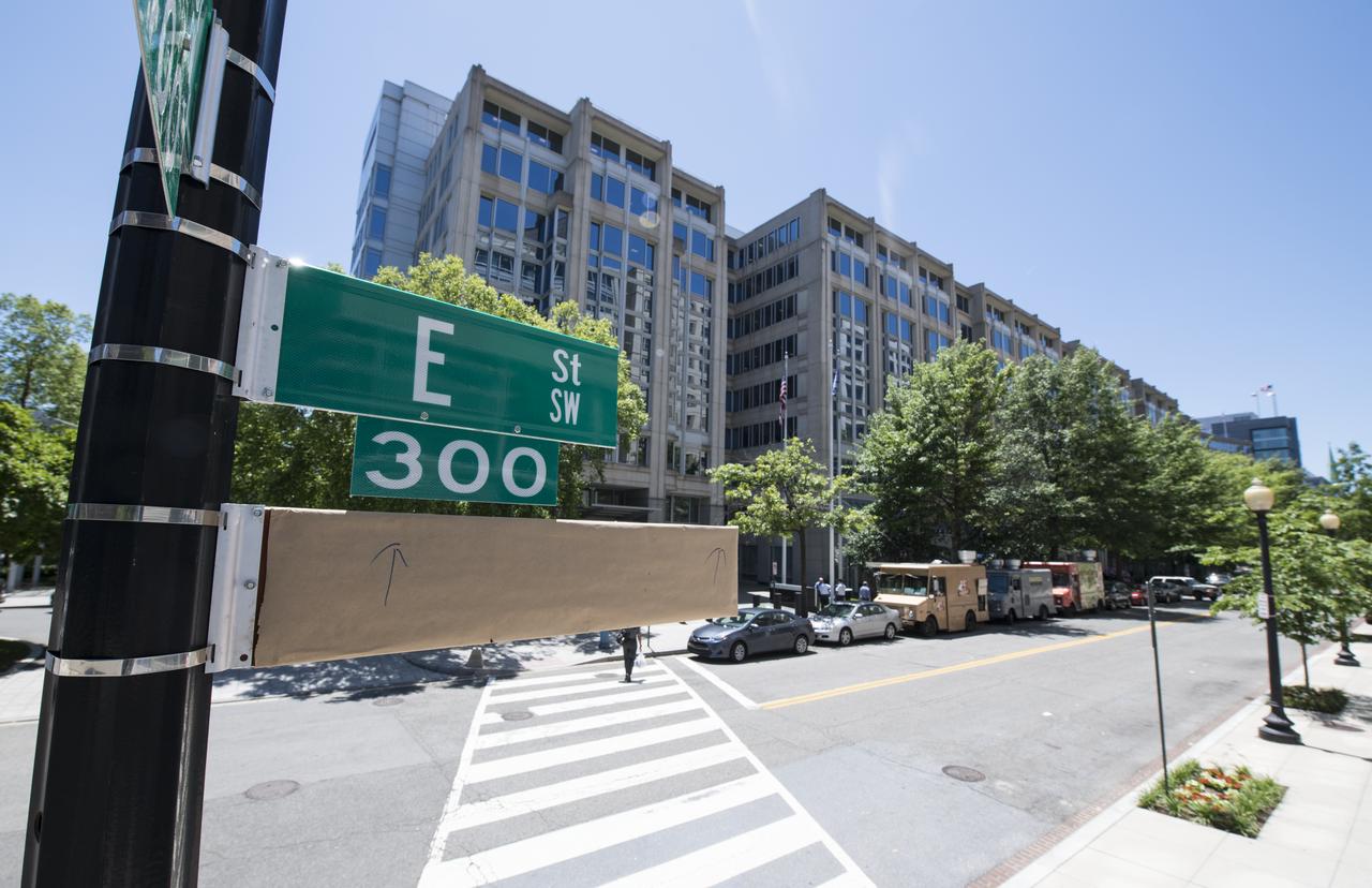 A covered street sign is seen outside of the NASA Headquarters building the day before a street renaming ceremony, Tuesday, June 11, 2019 in Washington, DC. On Wednesday, June 12, a ceremony was held to dedicate the 300 block of E Street SW in front of the NASA Headquarters building as "Hidden Figures Way" to honor Katherine Johnson, Dorothy Vaughan, Mary Jackson and all women who have dedicated their lives to honorably serving their country, advancing equality, and contributing to the space program of the United States. Photo Credit: (NASA/Joel Kowsky)