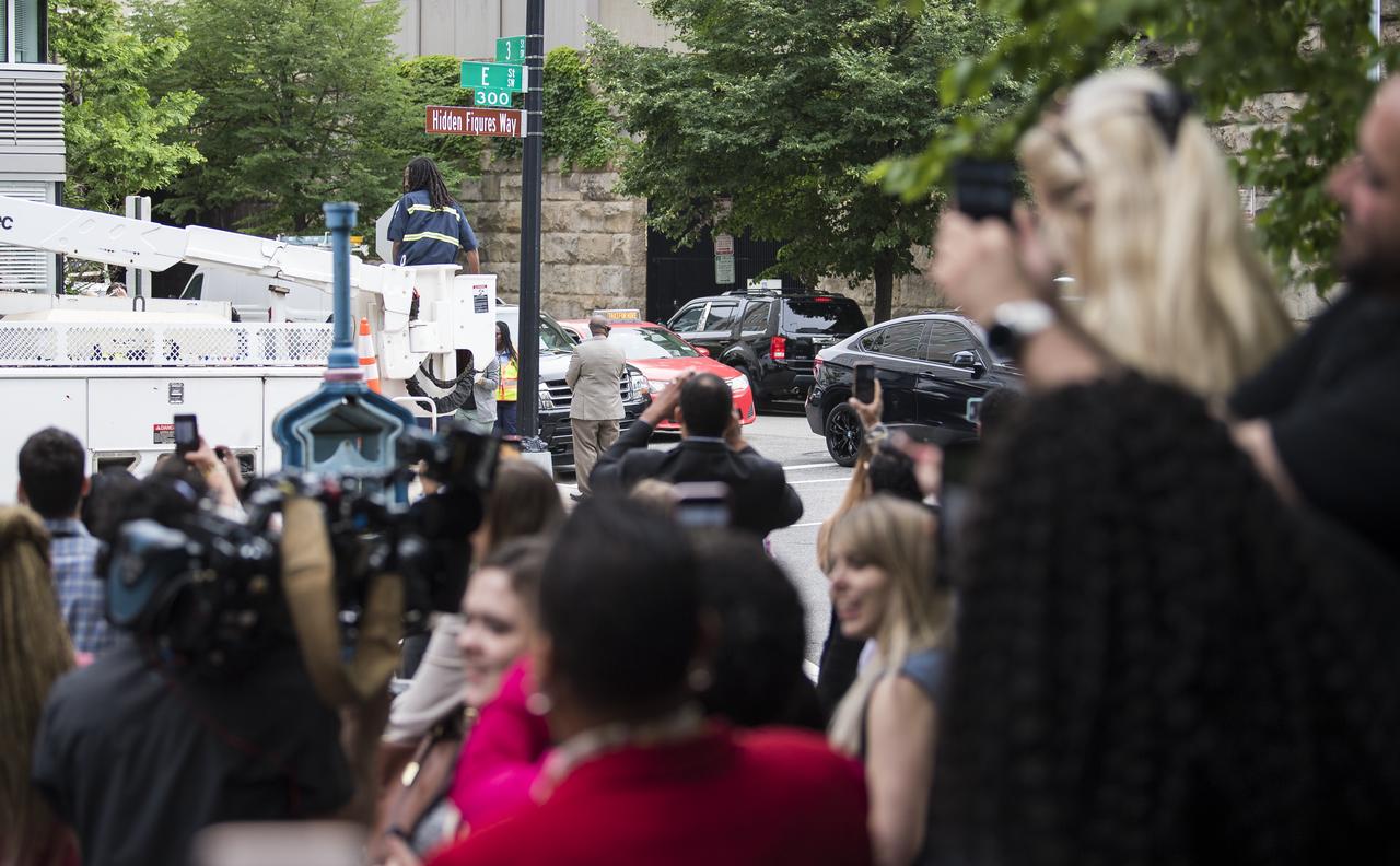 Attendees of the street dedication ceremony take pictures of the "Hidden Figures Way" street sign at the corner of 3rd and E Street SW following its unveiling, Wednesday, June 12, 2019 at NASA Headquarters in Washington, DC. The 300 block of E Street SW in front of the NASA Headquarters building was designated as "Hidden Figures Way" to honor Katherine Johnson, Dorothy Vaughan, Mary Jackson and all women who have dedicated their lives to honorably serving their country, advancing equality, and contributing to the space program of the United States. Photo Credit: (NASA/Joel Kowsky)