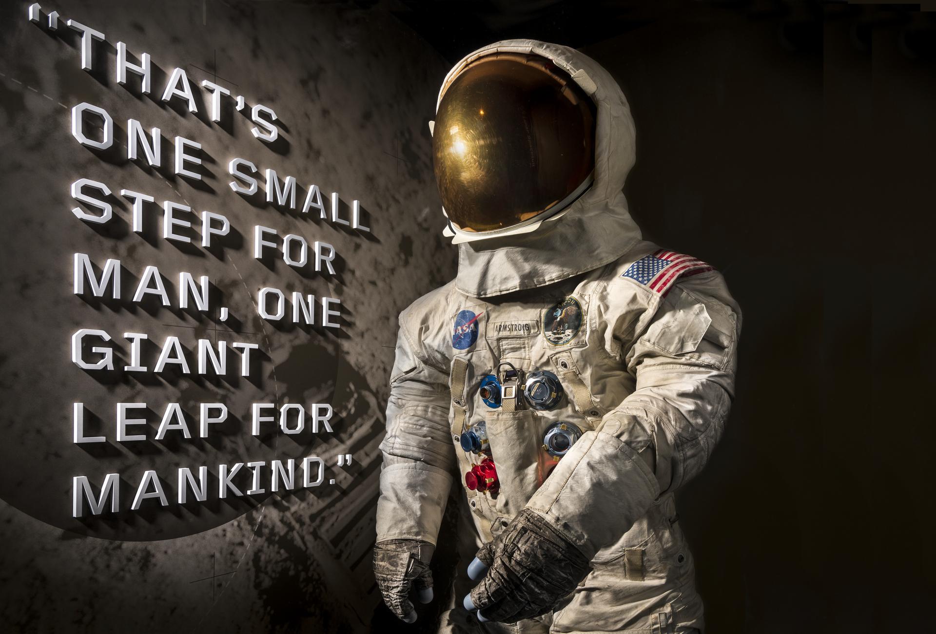 A spacesuit display showing Neil A. Armstrong's Pressure Suit, A7-L, which he wore to walk on the Moon, with the first words he spoke on the surface displayed behind the suit.