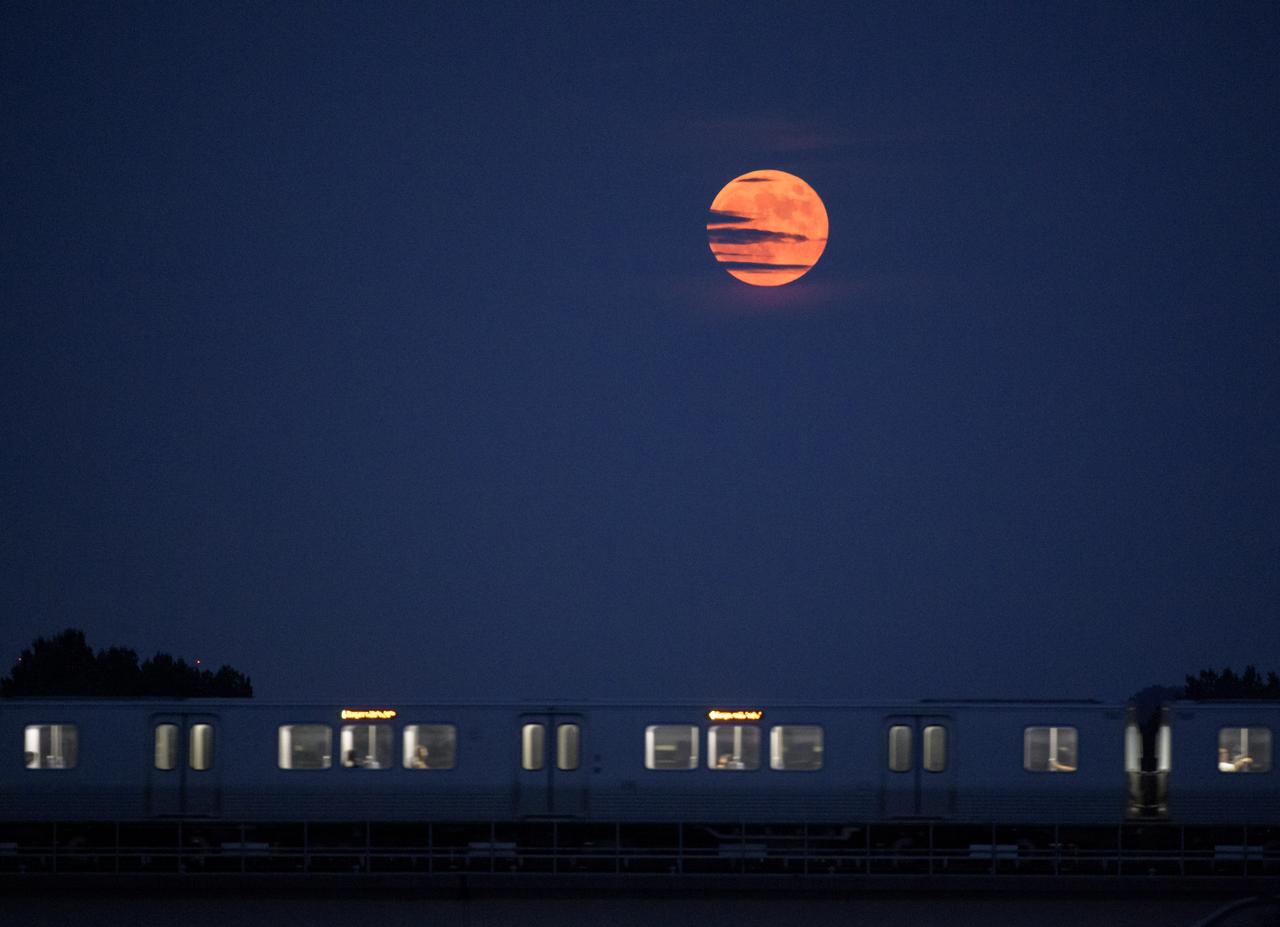 The Moon rises as a Metrorail car crosses the Potomac river in Washington 50 years to the day after astronauts Neil Armstrong, Michael Collins, and Buzz Aldrin launched on Apollo 11, the first mission to land astronauts on the Moon, Tuesday, July 16, 2019. Photo Credit: (NASA/Bill Ingalls)