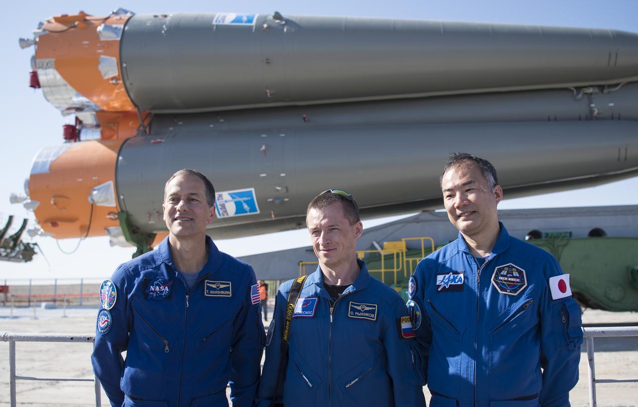 Expedition 60 backup crew members Thomas Marshburn of NASA, left, Sergey Ryzhikov of Roscosmos, center, and Soichi Noguchi of the Japan Aerospace Exploration Agency (JAXA), right, pose for a picture on the launch pad as the Soyuz rocket arrives at the launch pad by train, Thursday, July 18, 2019 at the Baikonur Cosmodrome in Kazakhstan. Expedition 60 Soyuz Commander Alexander Skvortsov of Roscosmos, flight engineer Andrew Morgan of NASA, and flight engineer Luca Parmitano of ESA (European Space Agency) are scheduled to launch aboard their Soyuz MS-13 spacecraft at 12:28 p.m. Eastern time (9:28 p.m. Baikonur time) , on Saturday, July 20. Photo Credit: (NASA/Joel Kowsky)
