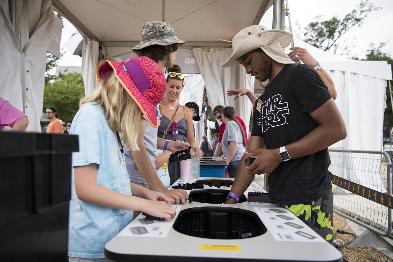 Visitors help build pieces of a 20 ft. rocket at the LEGO exhibit at the Apollo 11 50th Anniversary celebration on the National Mall, Thursday, July 18, 2019 in Washington. Apollo 11 was the first mission to land astronauts on the Moon and launched on July 16, 1969 with astronauts Neil Armstrong, Michael Collins, and Buzz Aldrin. Photo Credit: (NASA/Aubrey Gemignani)