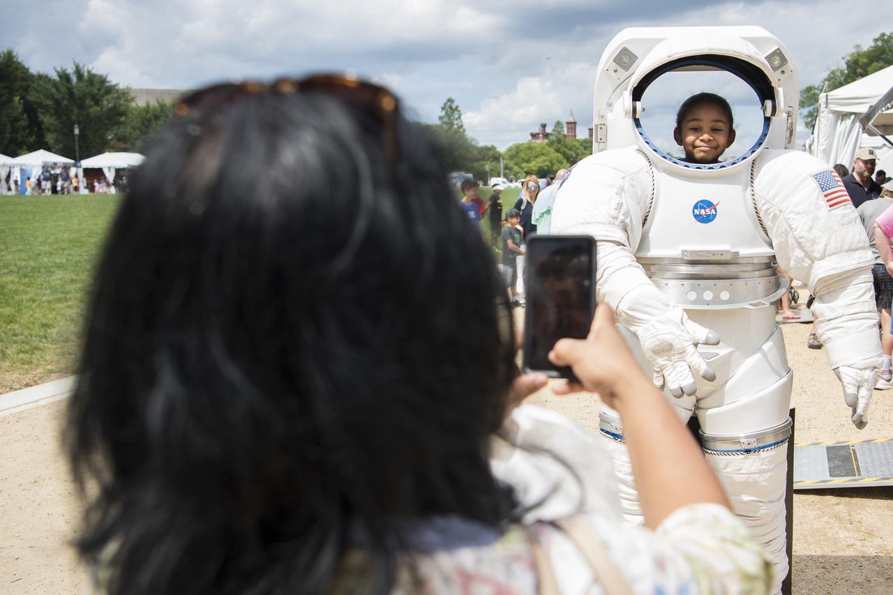A visitor poses for a photo in the NASA spacesuit at the Apollo 11 50th Anniversary celebration on the National Mall, Thursday, July 18, 2019 in Washington. Apollo 11 was the first mission to land astronauts on the Moon and launched on July 16, 1969 with astronauts Neil Armstrong, Michael Collins, and Buzz Aldrin. Photo Credit: (NASA/Aubrey Gemignani)