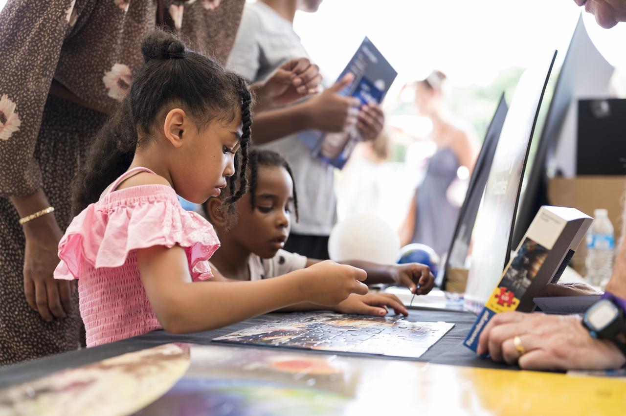 Visitors put a puzzle together at a NASA exhibit at the Apollo 11 50th Anniversary celebration on the National Mall, Thursday, July 18, 2019 in Washington. Apollo 11 was the first mission to land astronauts on the Moon and launched on July 16, 1969 with astronauts Neil Armstrong, Michael Collins, and Buzz Aldrin. Photo Credit: (NASA/Aubrey Gemignani)