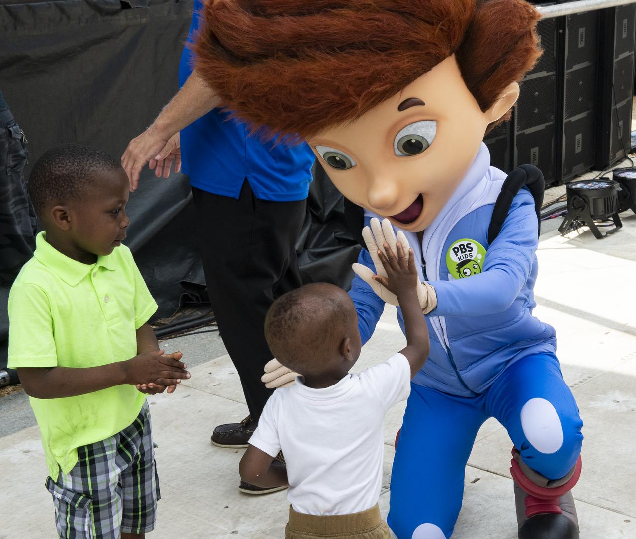 A visitor high fives Ready Jet Go's Jet Propulsion at the Apollo 11 50th Anniversary celebration on the National Mall, Thursday, July 18, 2019 in Washington. Apollo 11 was the first mission to land astronauts on the Moon and launched on July 16, 1969 with astronauts Neil Armstrong, Michael Collins, and Buzz Aldrin. Photo Credit: (NASA/Connie Moore)