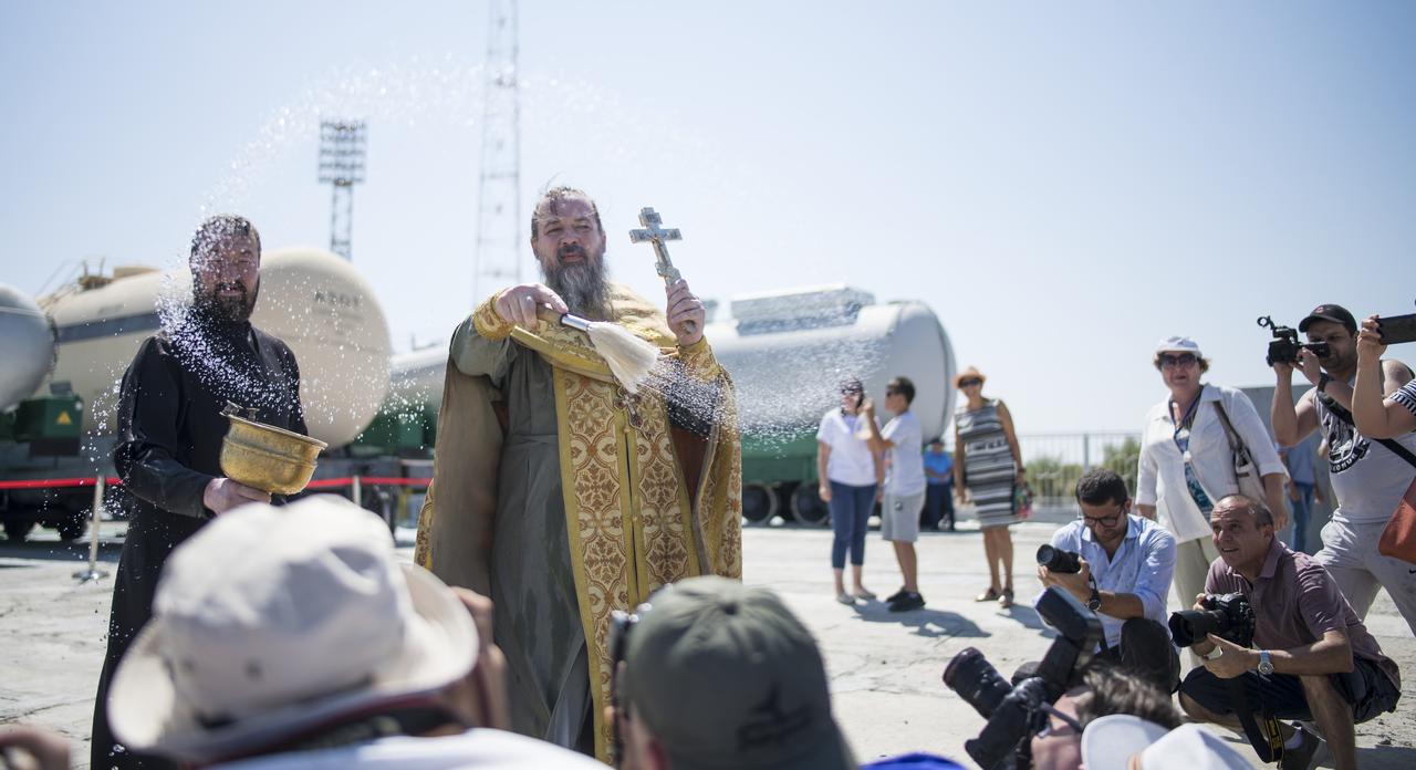 An Orthodox Priest blesses members of the media at the Baikonur Cosmodrome launch pad, Friday, July 19, 2019 in Kazakhstan. Expedition 60 Soyuz Commander Alexander Skvortsov of Roscosmos, flight engineer Andrew Morgan of NASA, and flight engineer Luca Parmitano of ESA (European Space Agency) are scheduled to launch to the International Space Station aboard the Soyuz MS-13 spacecraft on July 20. Photo Credit: (NASA/Joel Kowsky)