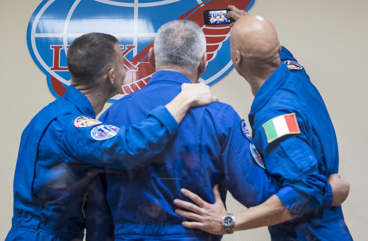 Expedition 60 flight engineer Andrew Morgan of NASA, left, Soyuz Commander Alexander Skvortsov of Roscosmos, center, and flight engineer Luca Parmitano of ESA (European Space Agency), right, take a selfie with the audience at the conclusion of a press conference, Friday, July 19, 2019 at the Cosmonaut Hotel in Baikonur, Kazakhstan. Morgan, Skvortsov, and Parmitano are scheduled to launch to the International Space Station aboard the Soyuz MS-13 spacecraft at 12:28 p.m. Eastern time (9:28 p.m. Baikonur time) on Saturday, July 20. Photo Credit: (NASA/Joel Kowsky)