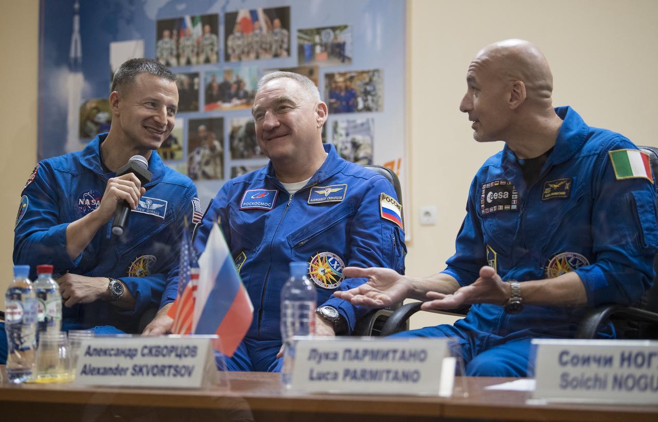 Expedition 60 flight engineer Andrew Morgan of NASA, left, Soyuz Commander Alexander Skvortsov of Roscosmos, center, and flight engineer Luca Parmitano of ESA (European Space Agency), right, are seen in quarantine, behind glass, during a press conference, Friday, July 19, 2019 at the Cosmonaut Hotel in Baikonur, Kazakhstan. Morgan, Skvortsov, and Parmitano are scheduled to launch to the International Space Station aboard the Soyuz MS-13 spacecraft at 12:28 p.m. Eastern time (9:28 p.m. Baikonur time) on Saturday, July 20. Photo Credit: (NASA/Joel Kowsky)