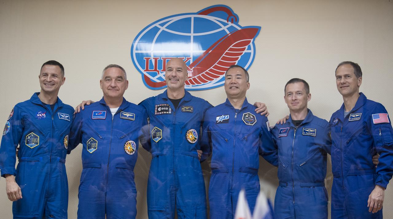 Expedition 60 prime crew members flight engineer Andrew Morgan of NASA, left, Soyuz Commander Alexander Skvortsov of Roscosmos, second from left, and flight engineer Luca Parmitano of ESA (European Space Agency), third from left, are seen with backup crew members Soichi Noguchi of the Japan Aerospace Exploration Agency (JAXA), third from right, Sergey Ryzhikov of Roscosmos, second from right, and Thomas Marshburn of NASA, right, pose for a picture at the conclusion of a press conference, Friday, July 19, 2019 at the Cosmonaut Hotel in Baikonur, Kazakhstan. Expedition 60 Soyuz Commander Alexander Skvortsov of Roscosmos, flight engineer Andrew Morgan of NASA, and flight engineer Luca Parmitano of ESA (European Space Agency) are scheduled to launch to the International Space Station aboard the Soyuz MS-13 spacecraft at 12:28 p.m. Eastern time (9:28 p.m. Baikonur time) on Saturday, July 20.  Photo Credit: (NASA/Joel Kowsky)