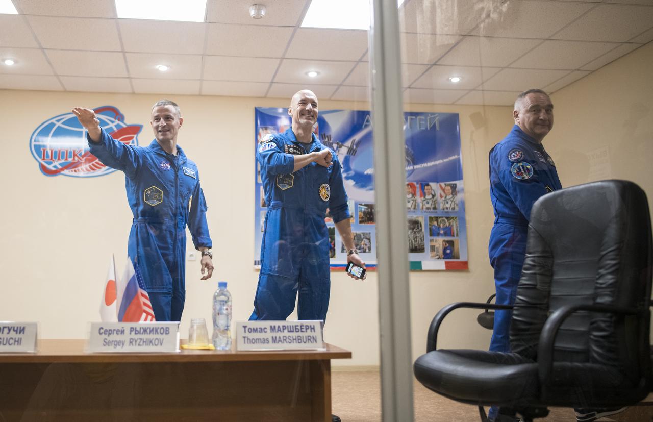 Expedition 60 flight engineer Andrew Morgan of NASA, flight engineer Luca Parmitano of ESA (European Space Agency), center, and Soyuz Commander Alexander Skvortsov of Roscosmos, right, are seen in quarantine, behind glass, as they leave a press conference, Friday, July 19, 2019 at the Cosmonaut Hotel in Baikonur, Kazakhstan. Morgan, Parmitano, and Skvortsov are scheduled to launch to the International Space Station aboard the Soyuz MS-13 spacecraft at 12:28 p.m. Eastern time (9:28 p.m. Baikonur time) on Saturday, July 20. Photo Credit: (NASA/Joel Kowsky)