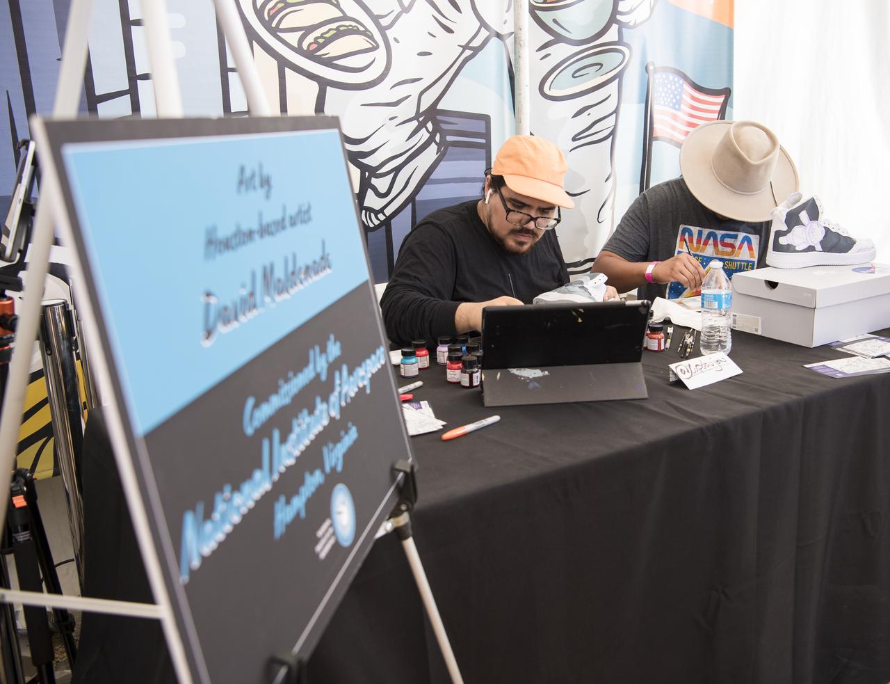 Artist David Maldonado paints a pair of high top shoes with a space themed design at the Apollo 11 50th Anniversary celebration on the National Mall, Friday, July 19, 2019 in Washington. Apollo 11 was the first mission to land astronauts on the Moon and launched on July 16, 1969 with astronauts Neil Armstrong, Michael Collins, and Buzz Aldrin. Photo Credit: (NASA/Aubrey Gemignani)