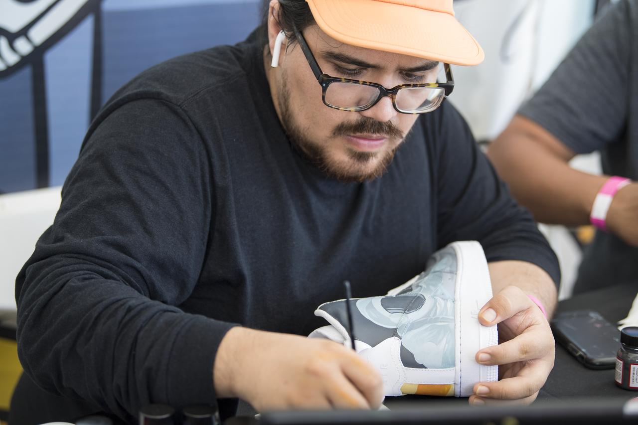Artist David Maldonado paints a pair of high top shoes with a space themed design at the Apollo 11 50th Anniversary celebration on the National Mall, Friday, July 19, 2019 in Washington. Apollo 11 was the first mission to land astronauts on the Moon and launched on July 16, 1969 with astronauts Neil Armstrong, Michael Collins, and Buzz Aldrin. Photo Credit: (NASA/Aubrey Gemignani)