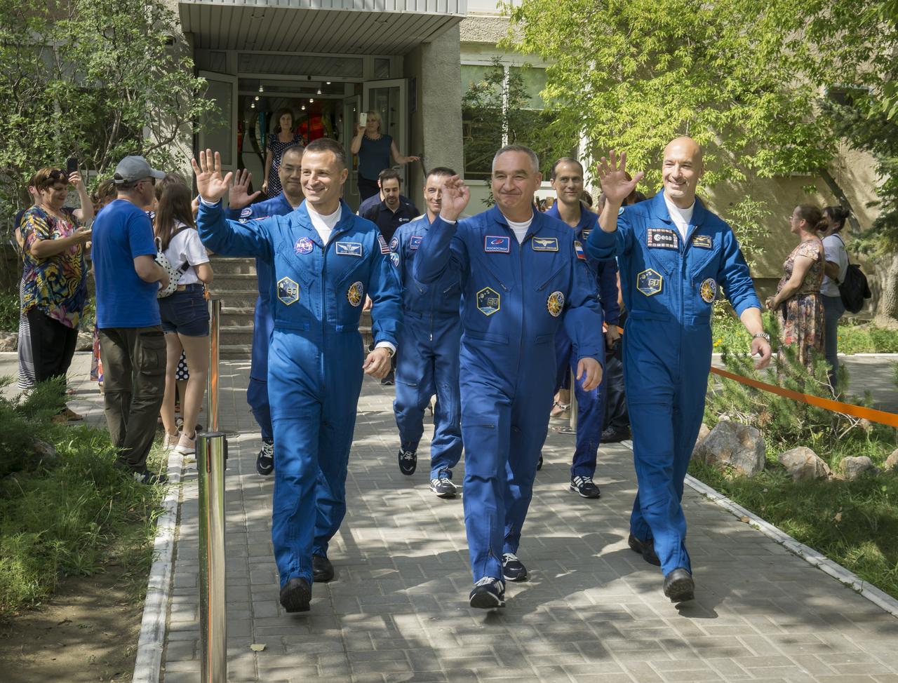 Expedition 60 flight engineer Andrew Morgan of NASA, left, Soyuz Commander Alexander Skvortsov of Roscosmos, center, and flight engineer Luca Parmitano of ESA (European Space Agency), right, wave as they depart the Cosmonaut Hotel to suit-up for their Soyuz launch to the International Space Station, Saturday, July 20, 2019 in Baikonur, Kazakhstan. Launch of the Soyuz MS-13 spacecraft with Skvortsov, Morgan, and Parmitano occurred at 12:28 p.m. Eastern time (9:28 p.m. Baikonur time) on July 20 beginning their mission to the International Space Station. Photo Credit: (NASA/Victor Zelentsov)