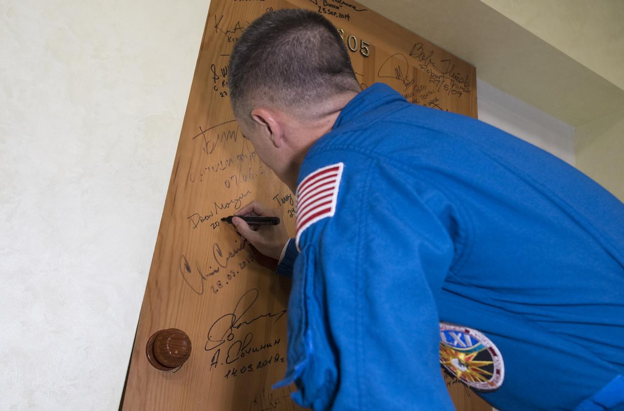 Expedition 60 flight engineer Andrew Morgan of NASA performs the traditional door signing at the Cosmonaut Hotel prior to departing the hotel for launch on a Soyuz rocket with fellow crewmates Alexander Skvortsov of Roscosmos and Luca Parmitano of ESA (European Space Agency), Saturday, July 20, 2019 in Baikonur, Kazakhstan. Skvortsov, Morgan, and Parmitano launched at 12:28 p.m. Eastern time (9:28 p.m. Baikonur time) to begin their mission to the International Space Station.  Photo Credit: (NASA/Joel Kowsky)