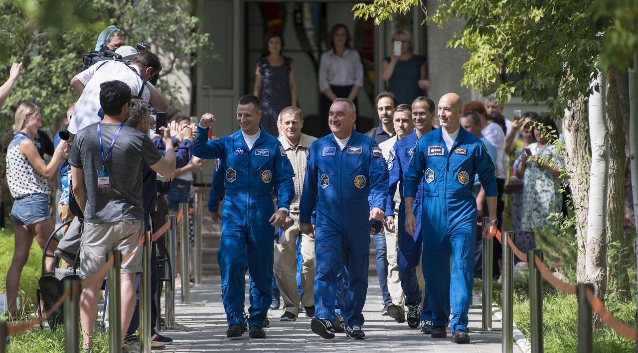 Expedition 60 flight engineer Andrew Morgan of NASA, left, Soyuz Commander Alexander Skvortsov of Roscosmos, center, and flight engineer Luca Parmitano of ESA (European Space Agency), right, wave as they depart the Cosmonaut Hotel to suit-up for their Soyuz launch to the International Space Station, Saturday, July 20, 2019 in Baikonur, Kazakhstan. Launch of the Soyuz MS-13 spacecraft with Skvortsov, Morgan, and Parmitano occurred at 12:28 p.m. Eastern time (9:28 p.m. Baikonur time) on July 20 beginning their mission to the International Space Station. Photo Credit: (NASA/Joel Kowsky)